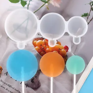 Gros plan d'un moule à sucettes rond en silicone à 3 cavités avec friandises colorées.