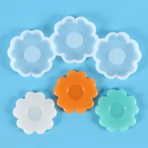 Detail view of flower-shaped silicone molds with colored resin flower samples on blue