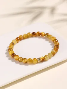 Macro detail of a golden tiger eye beaded bracelet with a decorative metal charm