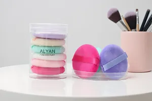 Detailed view of ALYAN multi-colored soft powder puffs in clear cylindrical storage case
