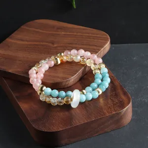 Close-up of multi-strand beaded bracelet with colorful natural stones and white ring.