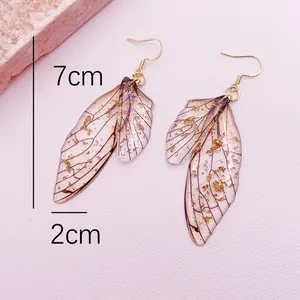 Close-up detail of handmade translucent pink cicada wing earrings with gold leaf flakes