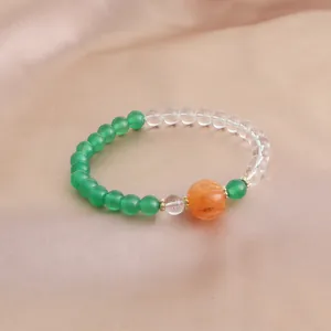 Detailansicht eines Armbands aus grünen Achaten und Kristallen mit orangefarbener Kürbisperle.
