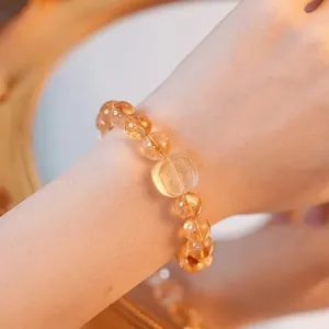 Gros plan d'un élégant bracelet en citrine avec un charm divin sculpté au poignet