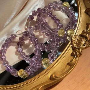 Close-up of Amethyst and Citrine crystal beaded bracelets on an ornate gold mirror