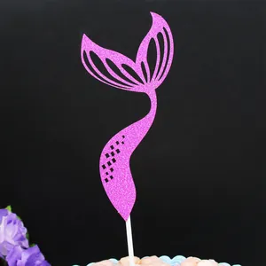 Detailed view of a pink glitter mermaid tail cake topper on a black background
