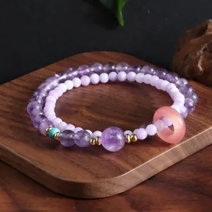 Close-up of double-layered amethyst and rose quartz beaded bracelet with pink ring detail