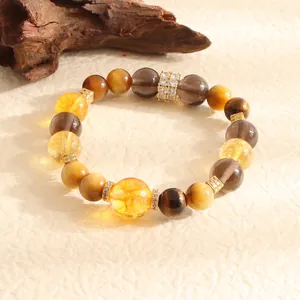 Close-up of natural tiger eye and yellow crystal beaded bracelet with gold accents for women