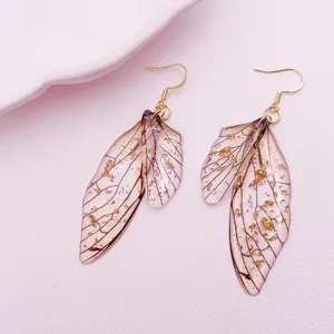 Detailed macro shot of vintage cicada wing earrings featuring embedded gold foil flakes.