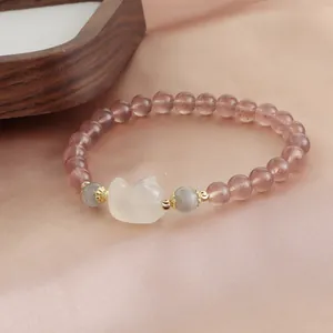 Detail view of strawberry quartz bracelet with a cute fox charm on pink silk.