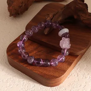 Detailed close-up of purple amethyst beaded bracelet with pink crystal fox pendant