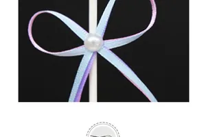 Close-up detail of blue and purple ribbon bow with pearl bead on cake topper decoration