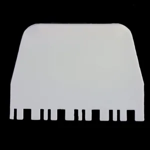 Close-up view of a white plastic cream scraper with serrated edge for cake decorating
