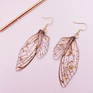 Detailed view of cicada wing earrings with gold foil and glitter embellishments.