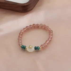 Close-up view of a natural strawberry quartz crystal beaded bracelet with elegant gold flower detail.