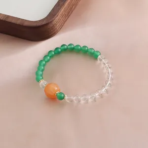 Detailaufnahme eines Armbands aus grünem Achat und klarem Kristall mit einer Kürbisperle
