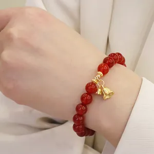 Nahaufnahme eines Armbands aus rotem Achat mit einem zarten goldenen Glöckchen
