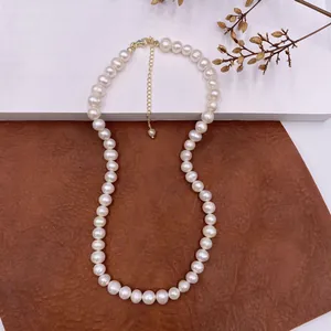 Close-up of an elegant natural pearl necklace with gold clasp on textured background.
