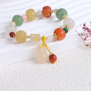 Makroansicht eines Naturstein-Perlenarmbands mit Kürbisperlen und Flaschenkürbis-Anhänger