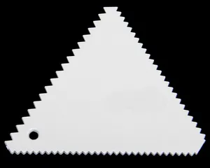 Detailed view of a white plastic triangle serrated scraper for cake cream decorating