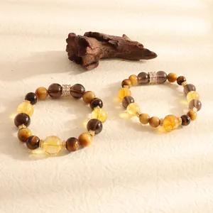 Detailed view of natural yellow quartz and tiger eye stone beads on a rustic wood background