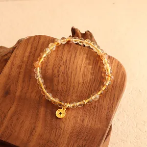 Detail eines Citrin-Armbands im neuen chinesischen Stil mit Goldmünzen-Anhänger auf Holz.