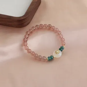 Close-up of a natural strawberry quartz bracelet with elegant white and green accent beads.