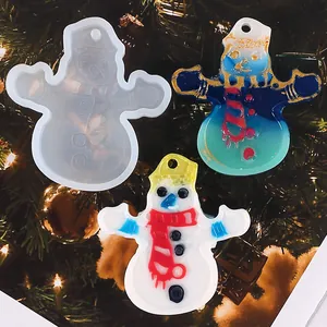 Detailed view of snowman resin molds and finished Christmas pendants on a tree background.