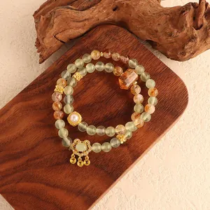 Detail shot of a double-layer green fluorite and yellow crystal bracelet with gold charms
