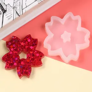 Close-up detail of cherry blossom silicone mold and finished red glitter resin flower.