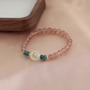Macro view of strawberry quartz beaded bracelet with gold flower charm and green beads