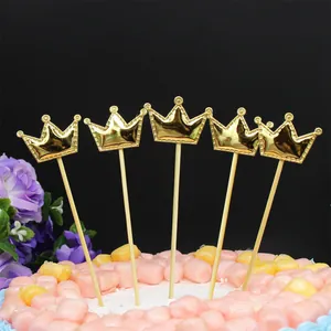Detalle de cinco adornos para tarta de cuero dorado con forma de corona sobre un pastel decorado