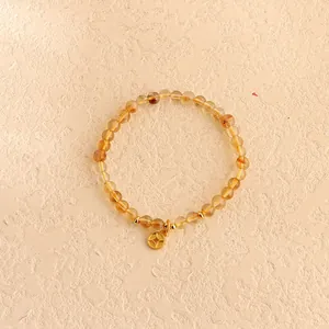 Detailansicht der gelben Zitrin-Kristallperlen und Goldmünzenanhänger an einem Armband.