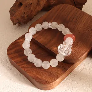 Detailed close-up of white agate beaded bracelet with nine-tailed fox carving on wood base