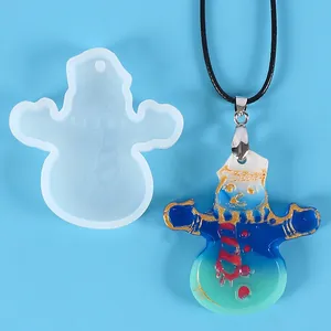 Detail of Christmas snowman silicone mold and finished resin pendant on blue background