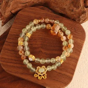 Close-up of natural green fluorite and yellow quartz beads with an ornate golden lock pendant