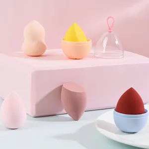Detailweergave van kleurrijke make-up sponsjes met eivormige opbergdoosjes op roze display.