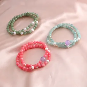 Elegant double-strand beaded bracelets with natural stones and pearls on silk background.