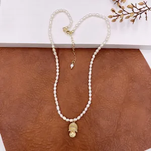 Detailed view of a vintage natural baroque pearl necklace with a gold Buddha pendant.