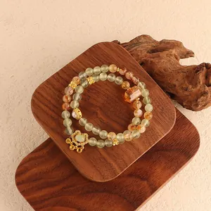 Close-up view of natural green fluorite and yellow rutilated quartz beads with golden charms.