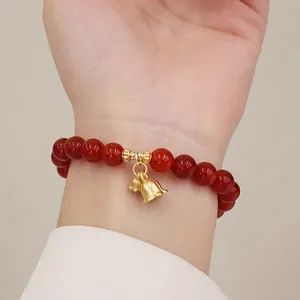 Nahaufnahme eines Armbands aus roten Achatperlen mit goldenen Anhängern