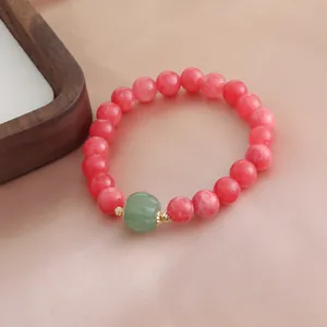 Elegante Makro-Detailansicht eines roten Steinperlenarmbands mit grüner Kürbis-Achatperle