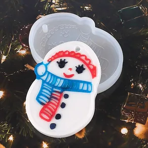 Christmas snowman silicone mold and resin pendant on a festive tree background.
