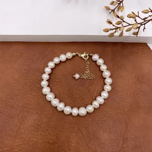 Close-up of elegant natural baroque pearl necklace with gold clasp on leather background