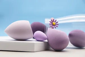 Gros plan d'éponges de maquillage violettes avec décoration de flacon marguerite