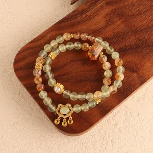 Macro detail of natural green fluorite and yellow crystal bracelet featuring a golden ruyi charm