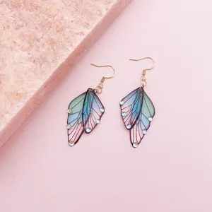 Detailed view of translucent gradient butterfly wing earrings with fine glitter accents.