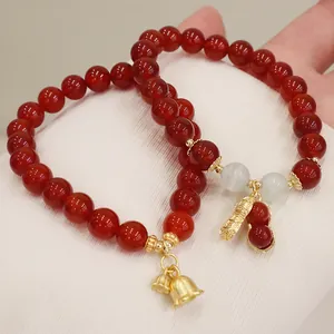 Detailaufnahme von roten Achat-Perlenarmbändern mit goldenen Erdnuss- und Glockenanhängern