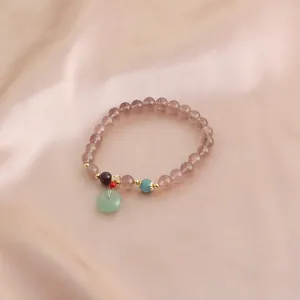 Detail view of natural strawberry quartz bracelet with a green jade-style pendant.