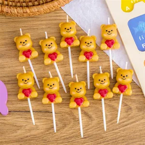 A set of ten adorable yellow teddy bear birthday candles featuring red heart details